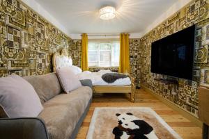 a living room with a couch and a flat screen tv at Deluxe 2 Bed Versace Bungalow Hot Tub, Sky TV, Cinema Screen Saffron Walden in Saffron Walden