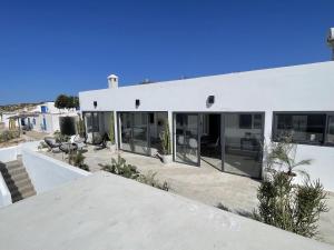 a white house with glass doors and a patio at Dar Bouba, Cap Sim : la maison sur l'Océan in Wassane
