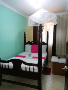 ein Schlafzimmer mit einem Himmelbett in der Unterkunft Milimani Greens Inn in Kakamega