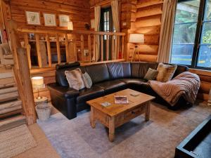 a living room with a leather couch and a coffee table at Newland Valley Log Cabins in Ulverston
