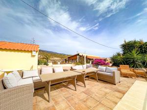 d'une terrasse avec des canapés et des tables. dans l'établissement Exquisite rural house with garden, pool and sea views, à Arico Viejo