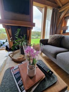 Newland Valley Log Cabins في أولفيرستون: غرفة معيشة مع أريكة وطاولة مع زهور