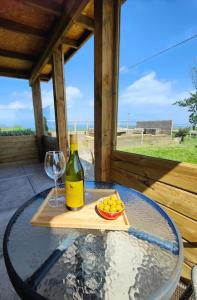 einen Glastisch mit einer Flasche Wein und einer Schale Obst in der Unterkunft Little Swelle Cabin with awesome Sea views in Poundstock