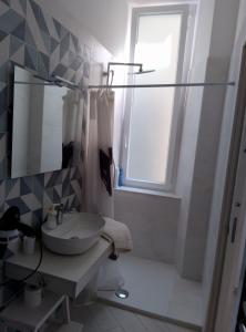 een badkamer met een wastafel, een spiegel en een raam bij Rooms add e criatur in Napels