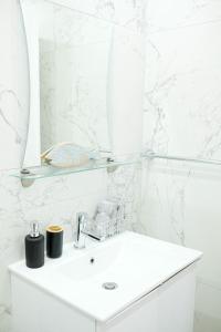 a white bathroom with a sink and a mirror at Lima Residence in Nicosia