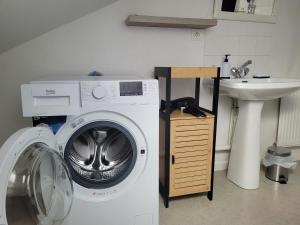 een wasmachine in een badkamer naast een wastafel bij Appartement T3 60m2 calme in Morez