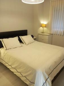 a bedroom with a large white bed and a lamp at Madrid Las Tablas apartments in Madrid