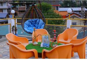um parque infantil com cadeiras laranja e um baloiço em Hotel Hilltop At Mall Road Manali With Open Terrace em Manali