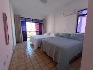 a bedroom with two beds and a large window at HostellHouse Márcia Guimarães in João Pessoa