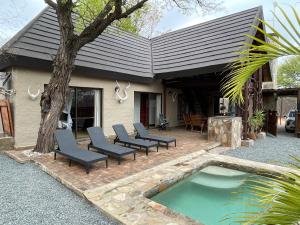 a patio with chairs and a pool in front of a house at The Cheetah Rest in Hoedspruit