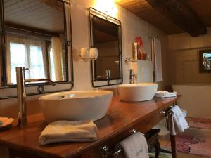 łazienka z 2 umywalkami na drewnianym blacie w obiekcie Les Quatre Saisons - balcon et jardin w mieście Val-d'Illiez