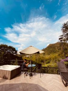 a person sitting at a table with an umbrella at GLAMPING EL PARAÍSO in Sasaima