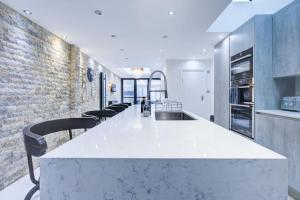 a kitchen with a white counter and a brick wall at Luxurious House Leyton sleep7+garden next to Stratford in London