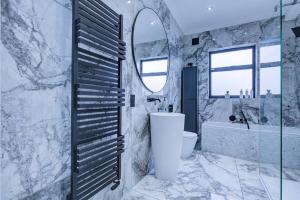 a bathroom with a tub and a sink and a mirror at Luxurious House Leyton sleep7+garden next to Stratford in London