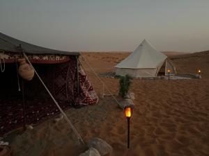 ein Zelt in der Wüste mit einer Taschenlampe im Sand in der Unterkunft Thousand Stars Desert Camp in Badīyah