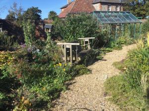 a garden with a greenhouse in the background at STACK YARD COTTAGE. in Cambridge