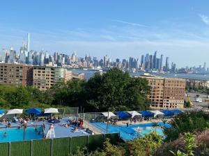 a large swimming pool with a city in the background at Lovely Cozy apt West NY NJ Excellent transportation 12 minutes to NY 7 minutes at NYWater Way Ferry in West New York