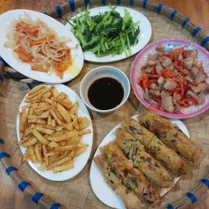 a table topped with plates of food and french fries at Tee Homestay hmong and trekking in Lao Cai