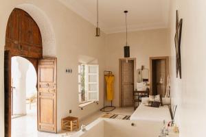 Riad La Lumière d'Étoile في مراكش: غرفة معيشة مع حوض استحمام وباب مفتوح
