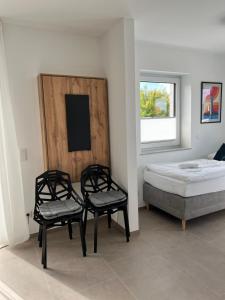 a bedroom with a bed and two chairs and a window at BnB Open Apartments Pader-Chill in Paderborn