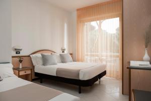 a hotel room with two beds and a window at Hotel Luxor in Milano Marittima