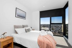 a bedroom with a white bed and a large window at Modern, Spacious 2BR Penthouse with Bay Views in Geelong