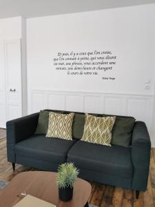 a couch in a living room with a quote on the wall at Appartement La palette in Villers-Semeuse