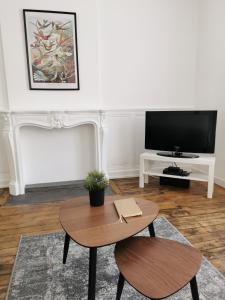 a living room with a table and a tv at Appartement La palette in Villers-Semeuse