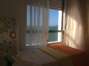 1 dormitorio con ventana y vistas al océano en Lexus Beira Mar - Apartamentos, en Florianópolis