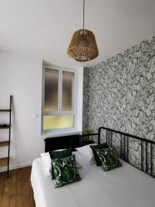 a bedroom with a white bed with green pillows at Appartement La palette in Villers-Semeuse