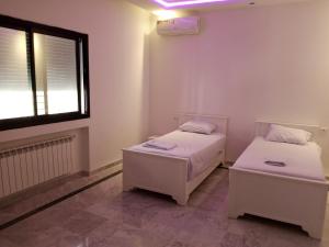 two beds in a small room with a window at Dar Nejib Apparts S1 S2 S3 et villa S4 in Nabeul
