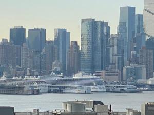 a city with cruise ships in the water and buildings at Lovely Cozy apt West NY NJ Excellent transportation 12 minutes to NY 7 minutes at NYWater Way Ferry in West New York