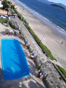 una vista aérea de una playa con sillas y una tienda azul en Lexus Beira Mar - Apartamentos, en Florianópolis