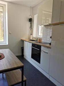 a kitchen with white appliances and a wooden table at Appartement La palette in Villers-Semeuse