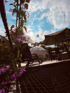 a patio with chairs and an umbrella and flowers at GLAMPING EL PARAÍSO in Sasaima