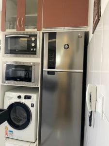 a kitchen with a stainless steel refrigerator and microwave at 1º Ap decorado do GALO em frente à ARENA MRV in Belo Horizonte