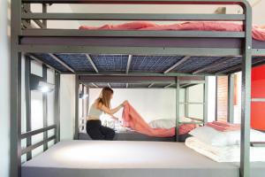 a woman is sitting on a bed in a bunk bed room at Balmers Hostel in Interlaken