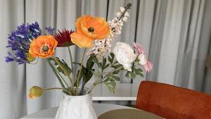 a white vase filled with colorful flowers on a table at bij DE RODE DEUR in Meppel