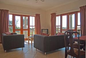 a living room with a couch and a table and windows at Hartley Manor Guest House in Muldersdrift