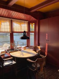 a dining room with a table and chairs and windows at Houseboat Amstel River Studio in Amsterdam