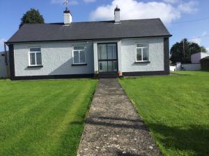 una casa con un césped verde delante de ella en Brigid M’s Farm House, en Killashandra