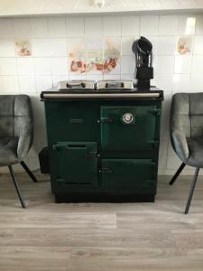 una estufa verde en una habitación con 2 sillas en Brigid M’s Farm House, en Killashandra
