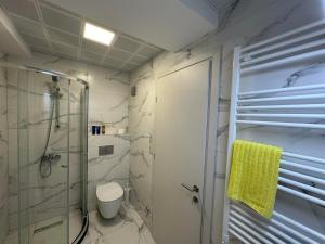 een badkamer met douche en toilet en een gele handdoek bij Royal Casa in Skopje +18 foto's