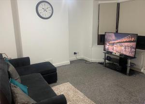 sala de estar con sofá, TV y reloj en Kingsway Lounge - Accomodation for Nuneaton Contractors & Industrial estate - Free Parking & WIFI Sleeps up to 7 people en Nuneaton