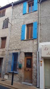um edifício de tijolos com janelas azuis e uma porta de madeira em Maison entière Coeur village em Argelès-sur-Mer