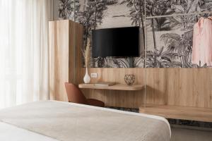 a bedroom with a bed and a tv on a wall at Hotel Luxor in Milano Marittima