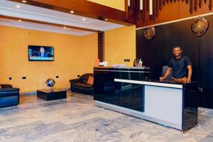 a man standing at a counter in a lobby at OVIC Hotel in Benin City