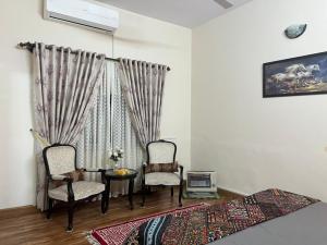 a bedroom with two chairs and a table and a window at Urban Lodge in Abbottabad