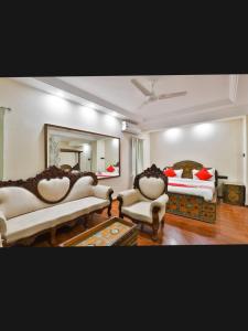 a bedroom with two beds and two chairs and a mirror at HOTEL SURYAKANT in Rajkot