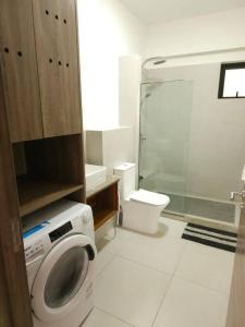 a bathroom with a shower and a washing machine at Amazing 2 bedrooms with garden in Quatre Bornes